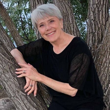 Charlotte Tomyn is a nice looking woman is smiling and sitting in a tree