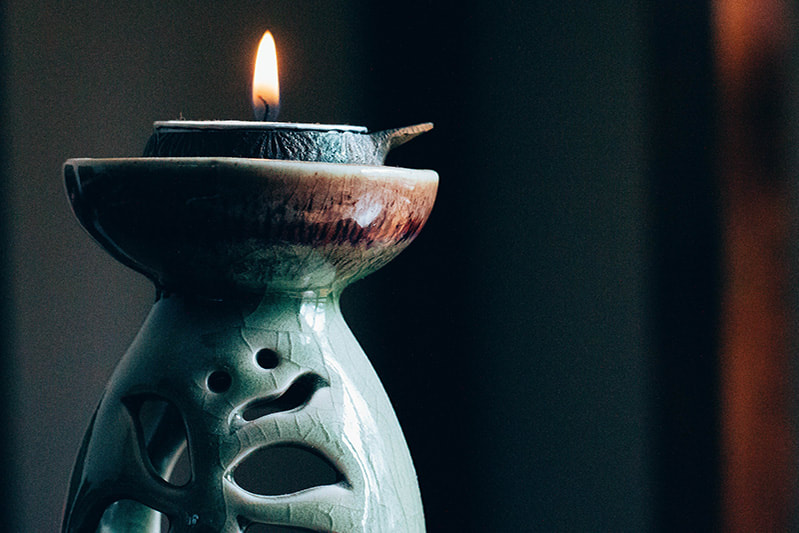 Candle burning on a decorative base.